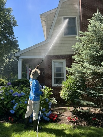 Clean N' Go technician soft washing a Nassau County home's siding